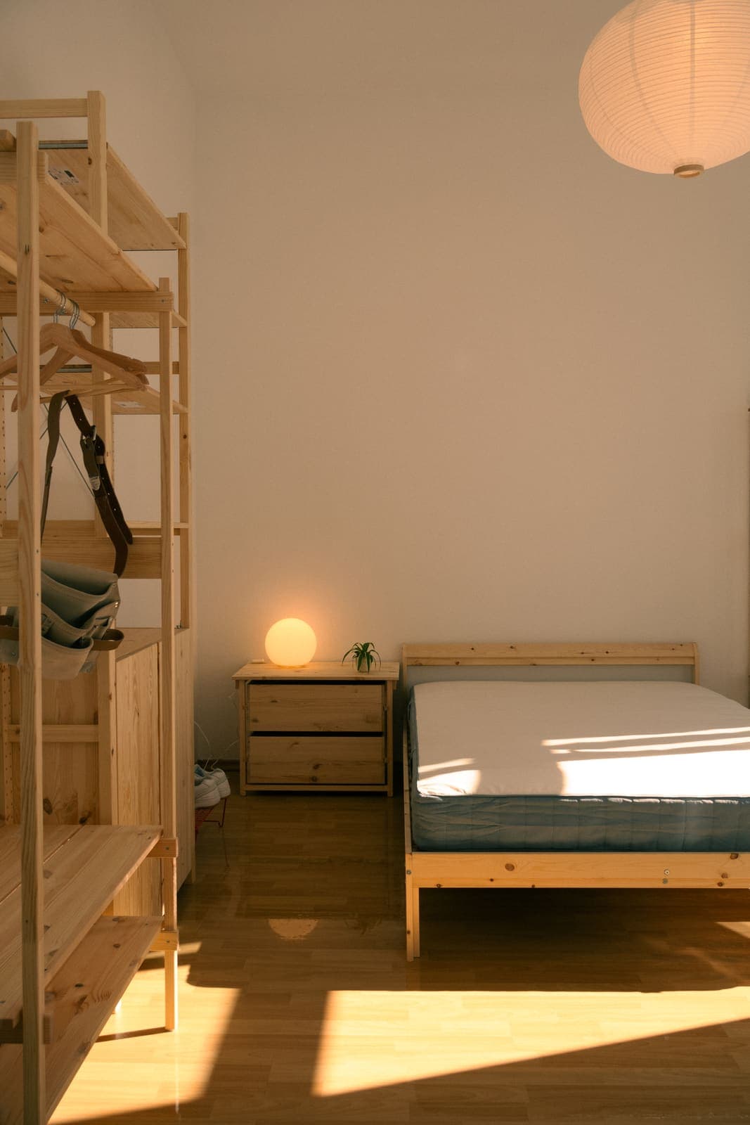 Möbliertes WG-Zimmer mit Bett, Nachttisch und Holzregal als Raumteiler